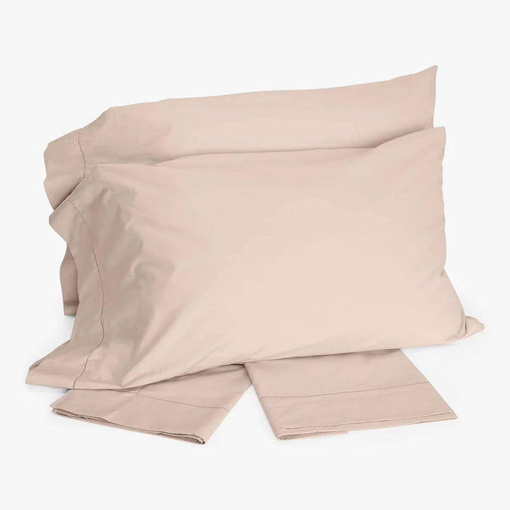 Simple beige bed linens with two pillowcases folded neatly.