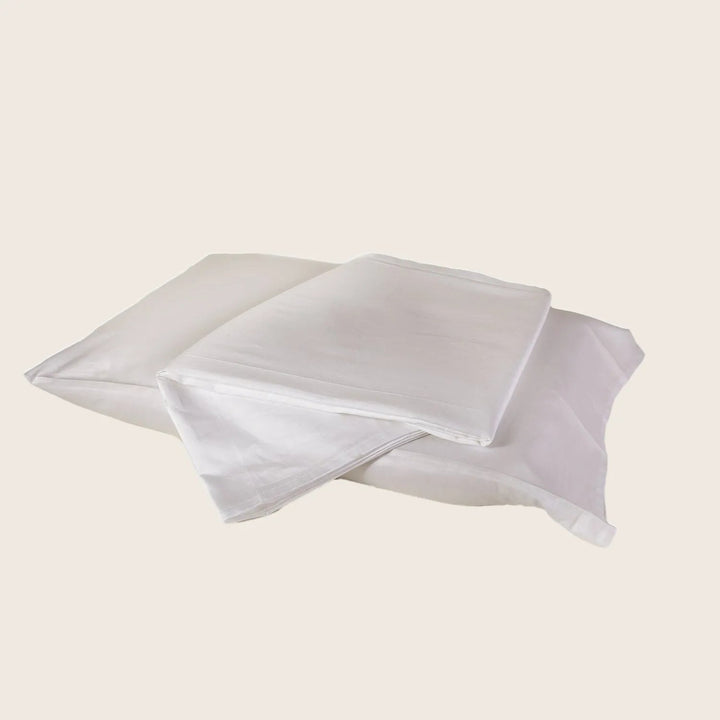 Neatly folded white bed linens on plain background, soft texture