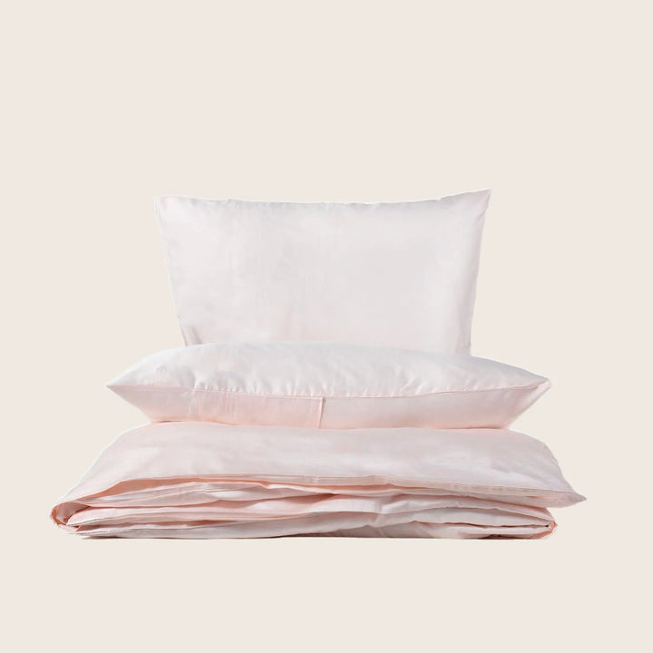 Set of fluffy pillows and folded pink bedding on display.