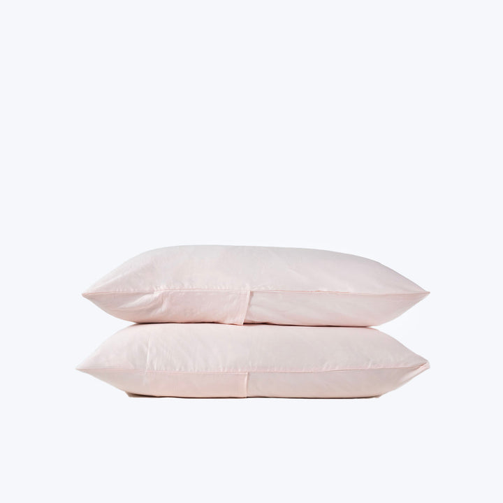 Two soft, stacked pink pillows on white background, comforting design.