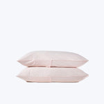 Two soft, stacked pink pillows on white background, comforting design.