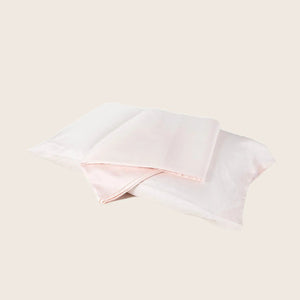 Two folded pillowcases in pink and white against white background.