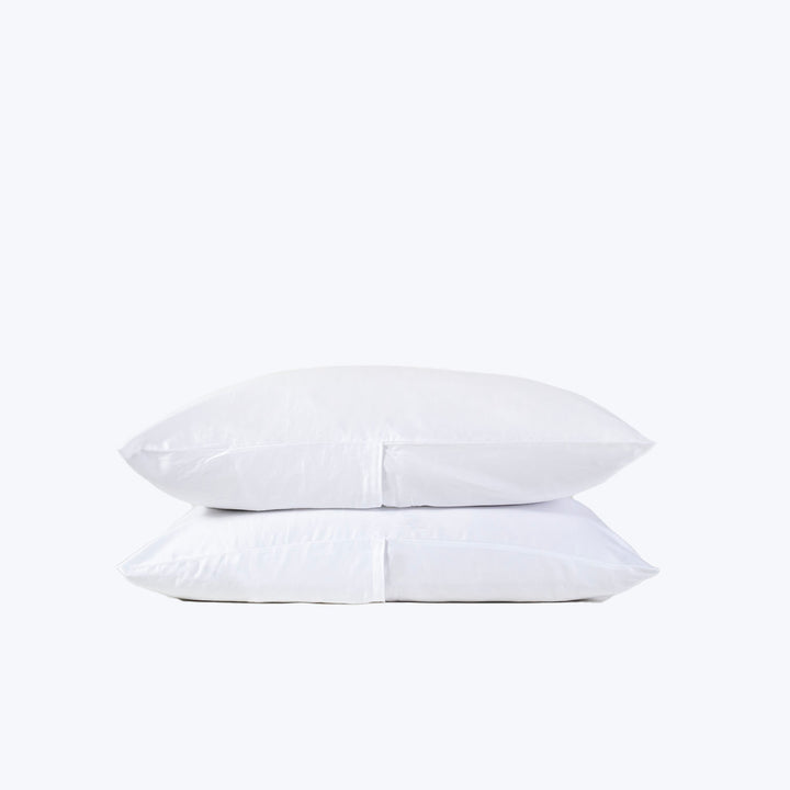 Freshly laundered white pillows stacked against plain white background.