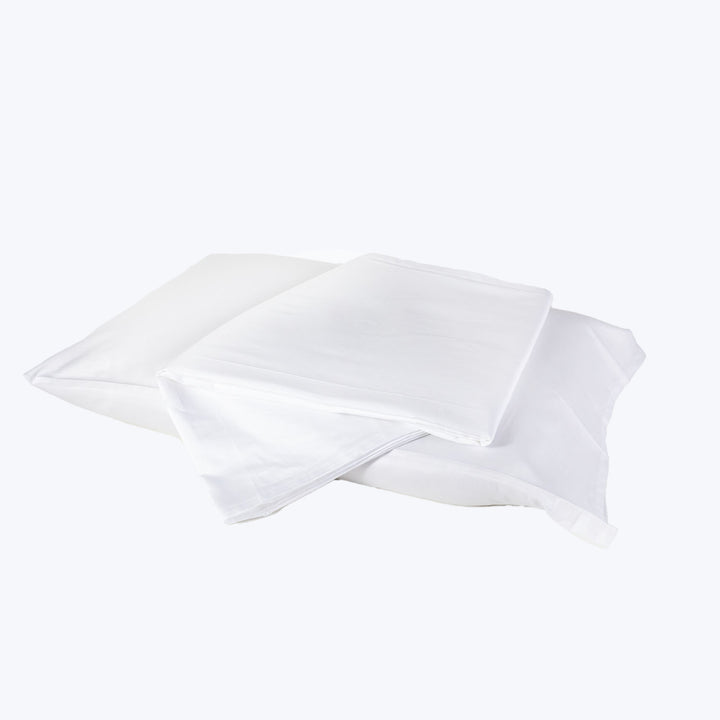White cotton pillowcases stacked neatly against soft white background.