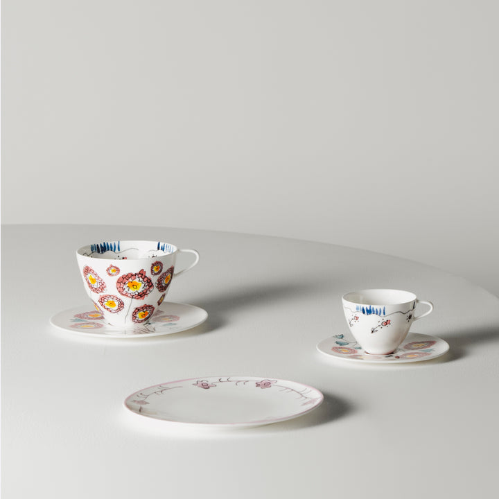 Two teacups on saucers, one with colorful floral motifs.