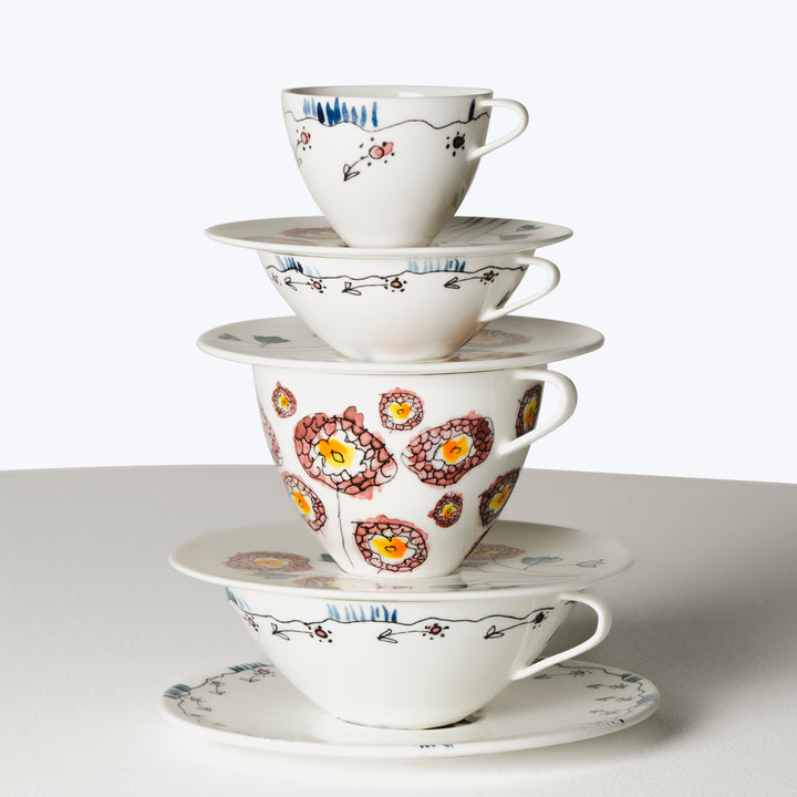 Colorful stack of three teacups with saucers in floral designs.