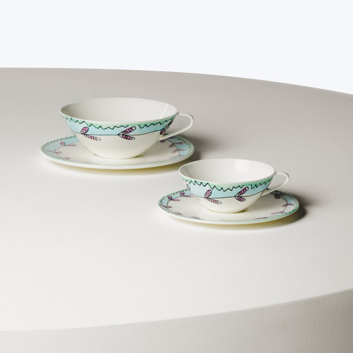 Two colorful teacups with saucers on a neutral tabletop surface