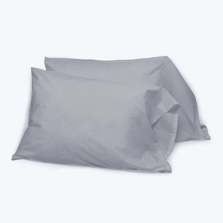 Two gray cotton pillowcases on white background, slightly wrinkled.