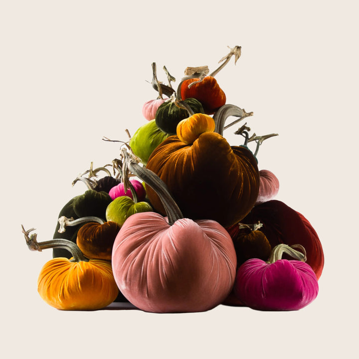 Group of colorful velvet pumpkins in various sizes stacked together.