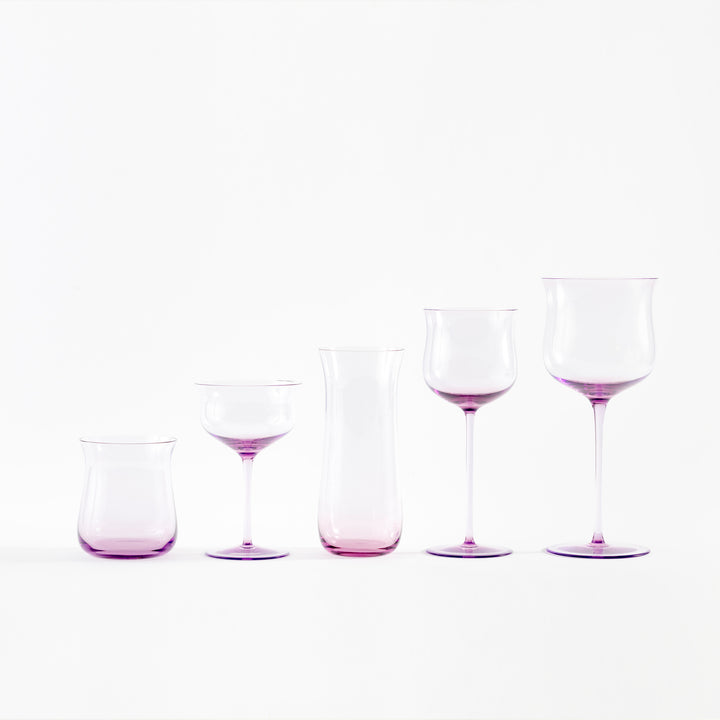 Minimalist arrangement of purple-tinted glassware against white background.