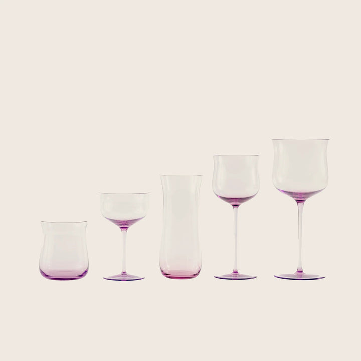 Minimalist arrangement of purple-tinted glassware against white background.