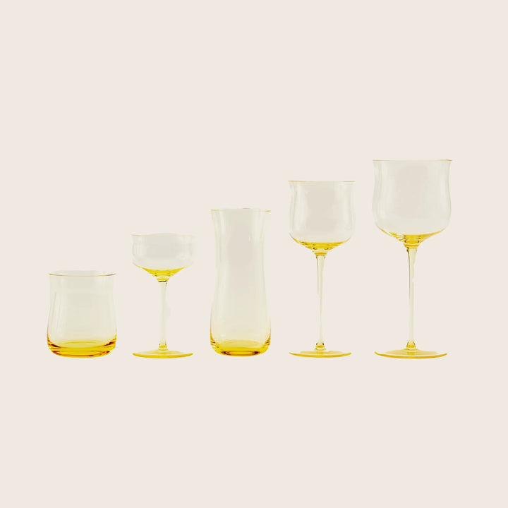Five modern yellow-tinted glass vessels for serving wine or cocktails.
