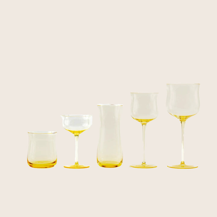 Five modern yellow-tinted glass vessels for serving wine or cocktails.