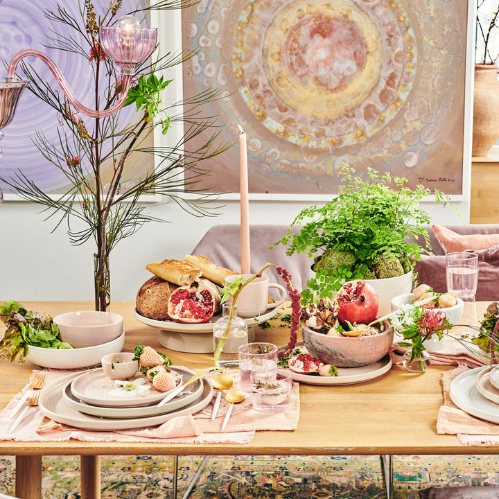 Elegantly styled dining table with eclectic dinnerware and lush greenery.