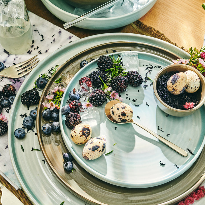 Elegantly styled table setting with decorative plate, berries, and quail eggs.