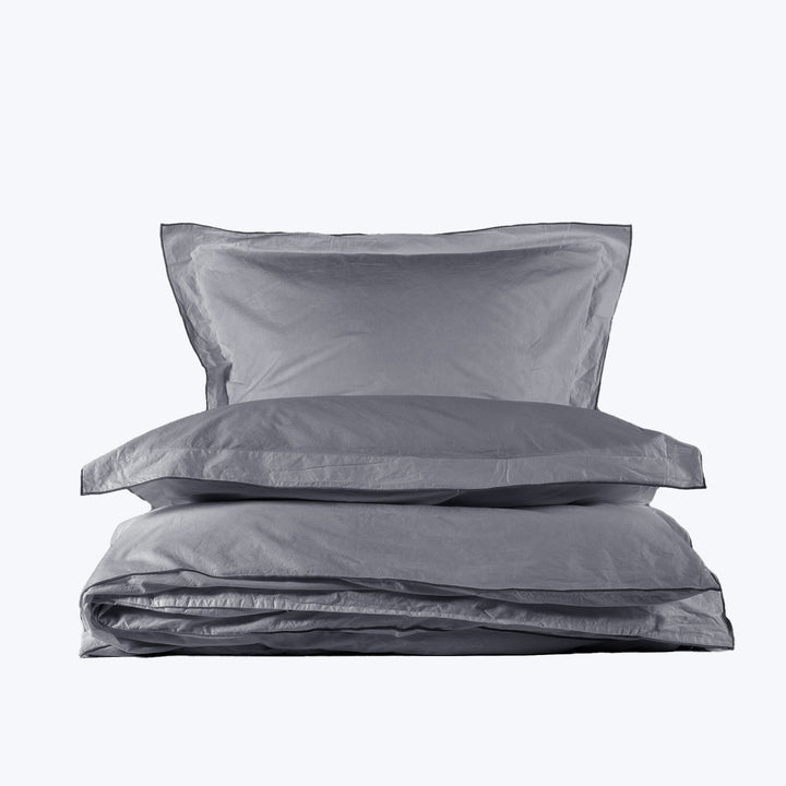 Minimalistic gray bedding set with two pillows on white background