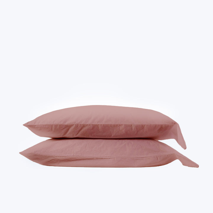 Pair of dusty pink rectangular pillows on white background display.