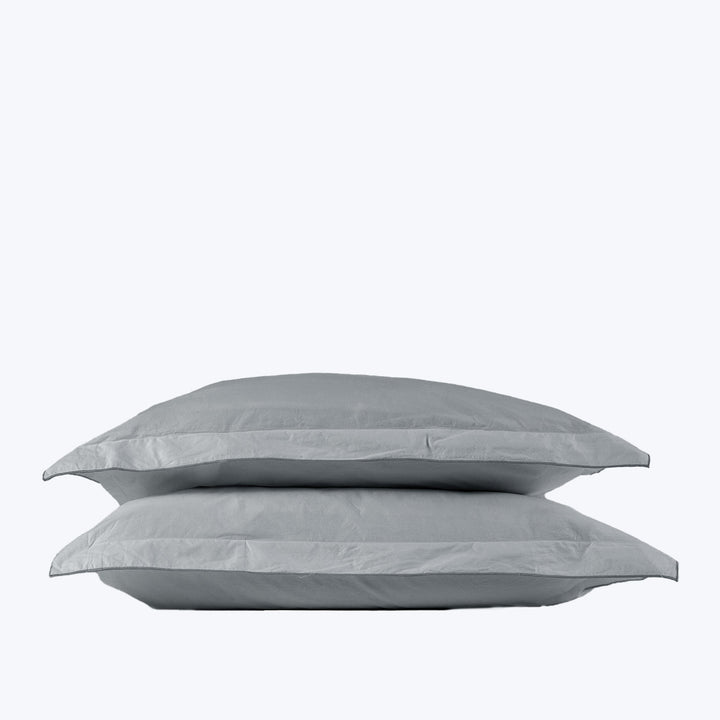 Two soft gray pillows stacked on white background, studio setting.