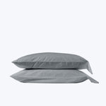 Two stacked gray pillows with pillowcases in light background setting.