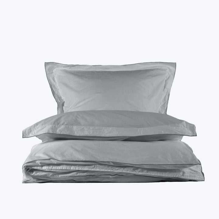 Neatly folded light gray bedding set on white background display