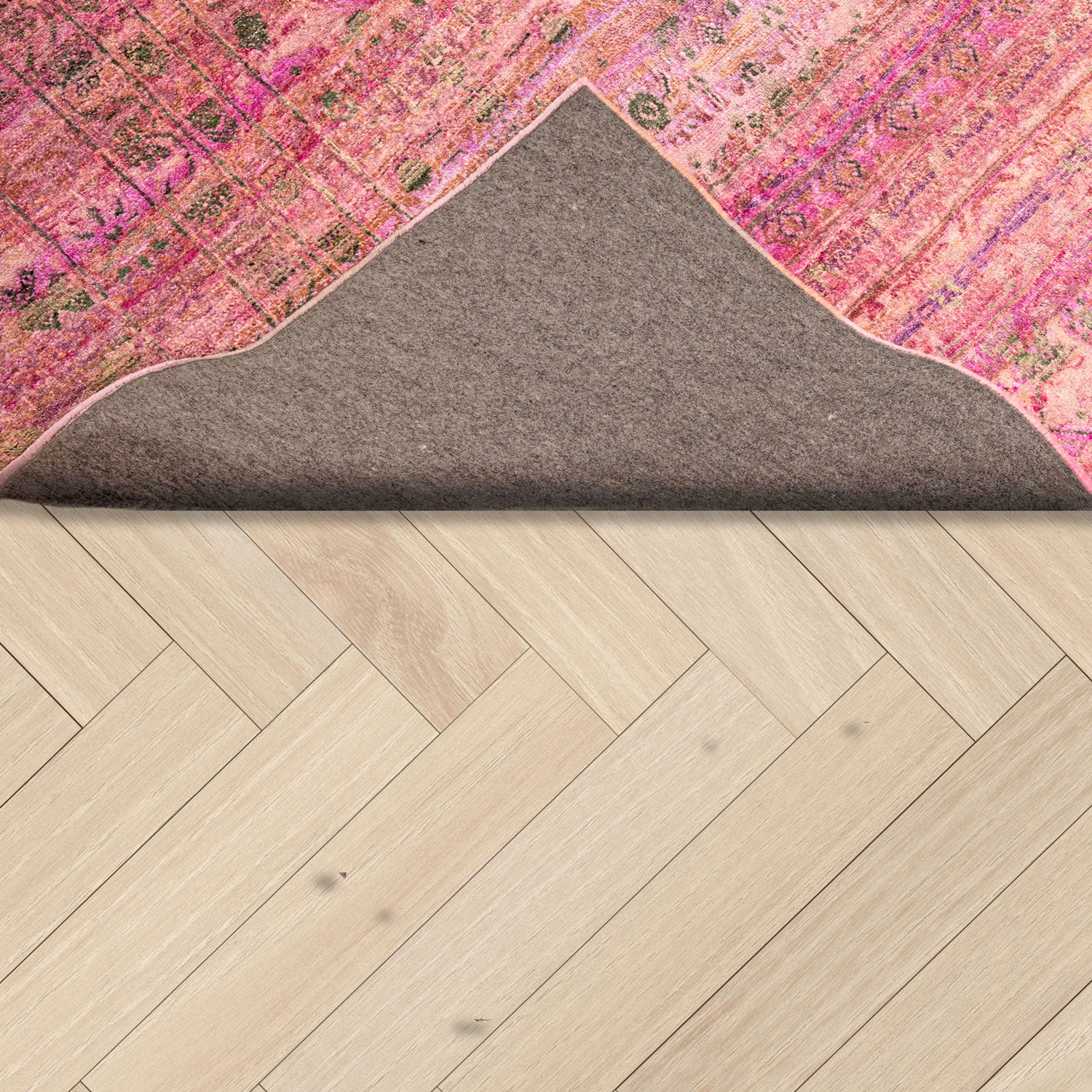 Close-up of colorful rug partially rolled on wooden herringbone floor.