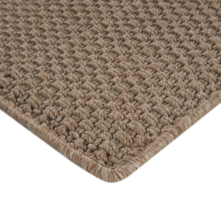 Close-up of beige woven area rug with textured pattern.