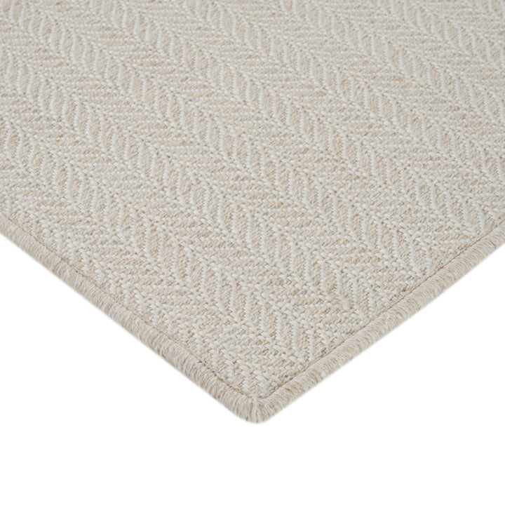 Close-up of light beige textured rug with herringbone pattern.