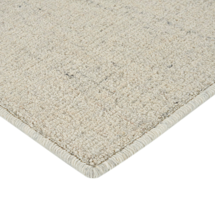 Close-up of soft, textured light-colored rug with bound border.