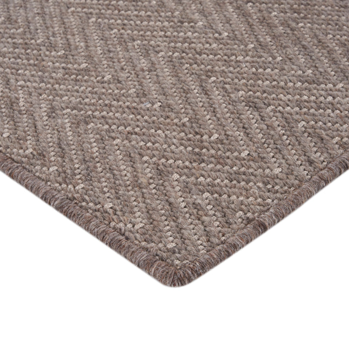 Close-up of textured herringbone rug in earthy brown tones.