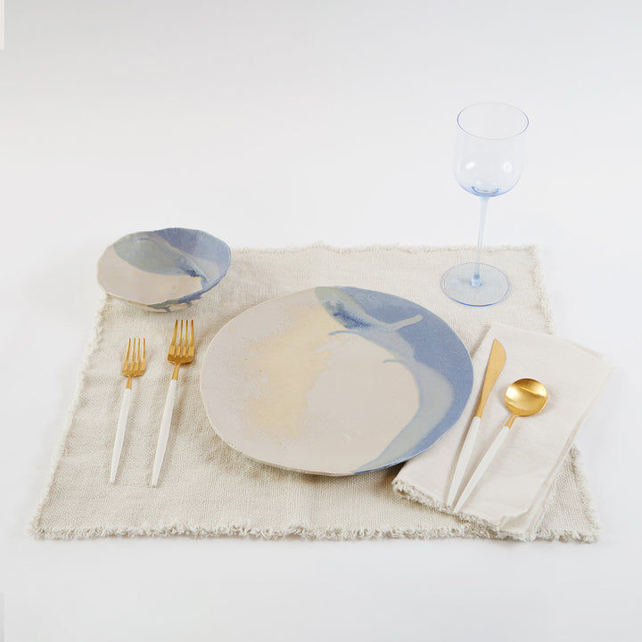 Elegantly set dining place with contemporary dinnerware and gold accents.
