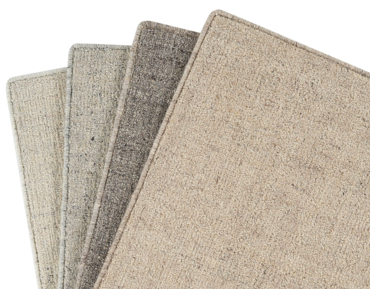 Assortment of carpet samples in neutral tones with visible texture.