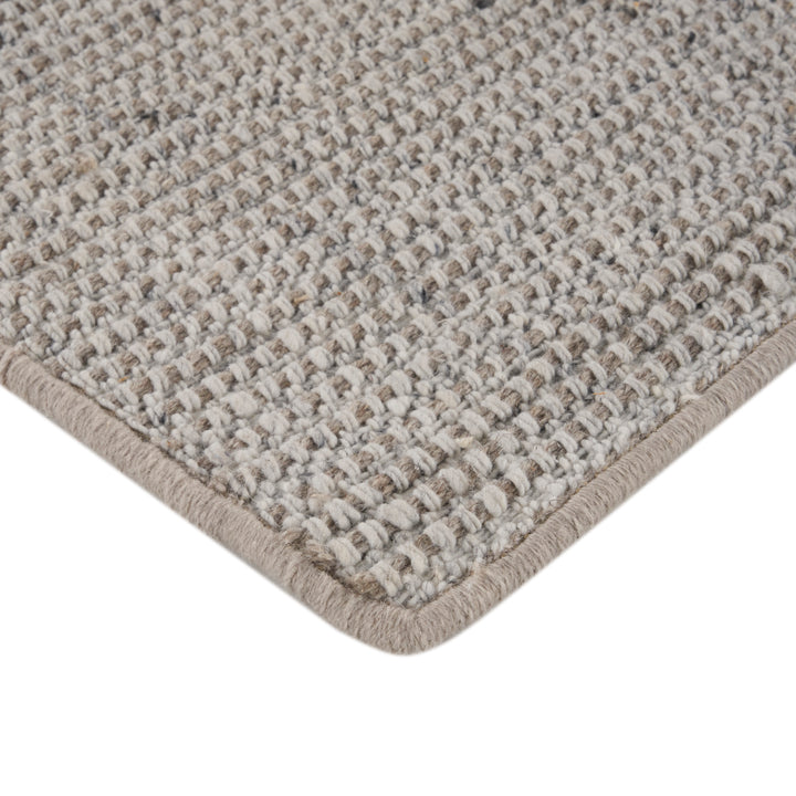 Close-up of woven carpet with beige and gray speckled texture.
