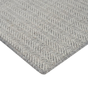 Close-up of light beige textured rug with herringbone pattern. - hover