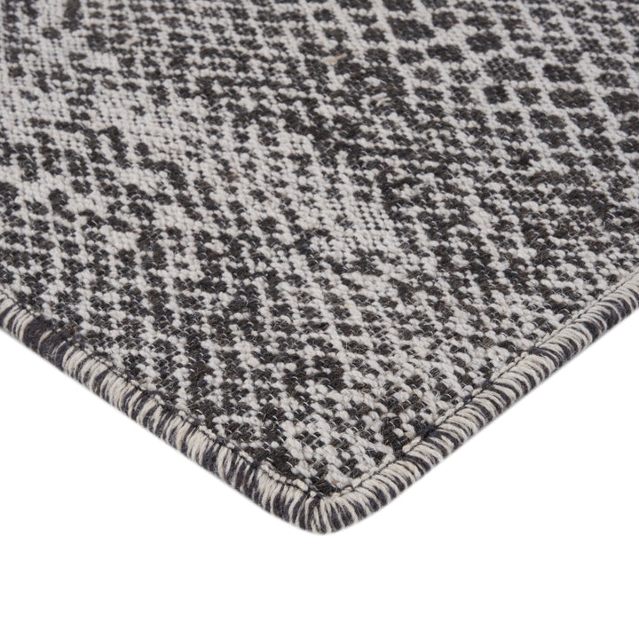 Close-up of houndstooth pattern on textured fabric, black and white.