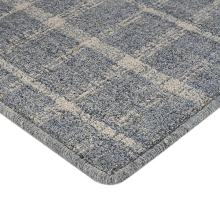 Close-up of blue checkered rug with plush texture and binding.