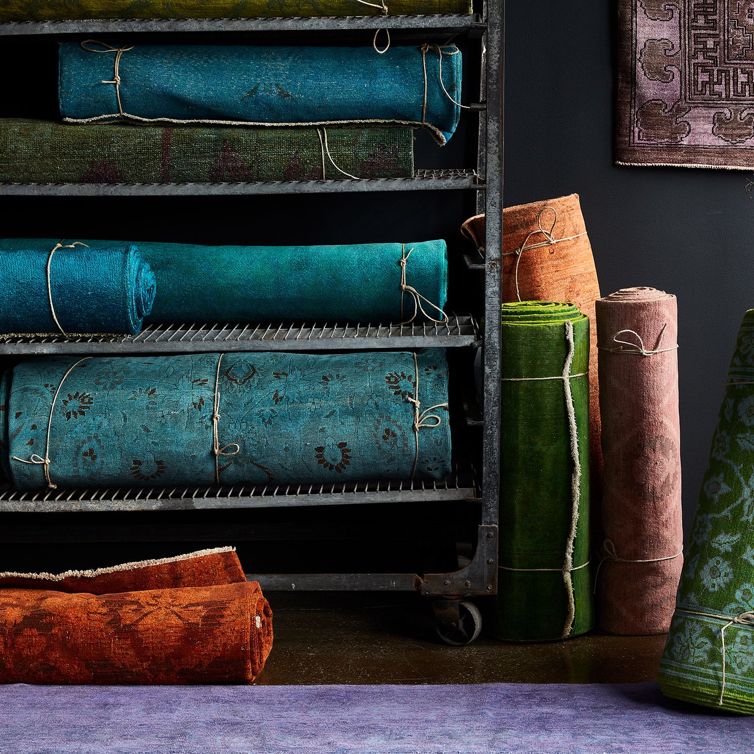 Colorful collection of vintage rugs displayed on movable storage rack.