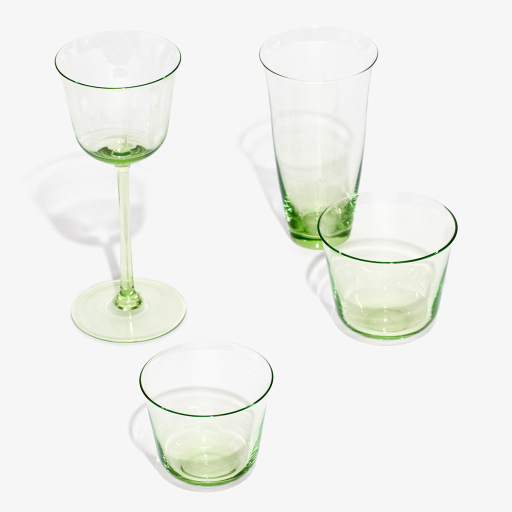 Four delicate green-tinted glasses on white background, various shapes.