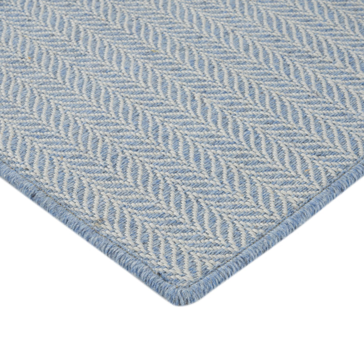 Close-up of blue herringbone pattern fabric with stitched border.