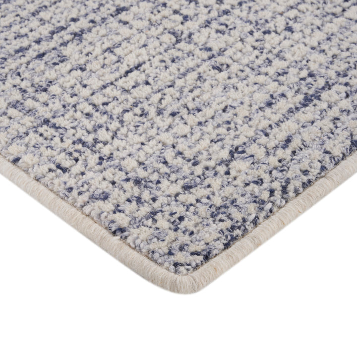 Close-up view of blue textured rug with plush tufted fibers.