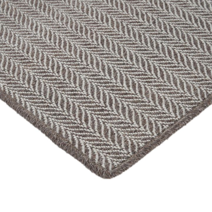 Close-up of herringbone pattern fabric in gray and cream colors.