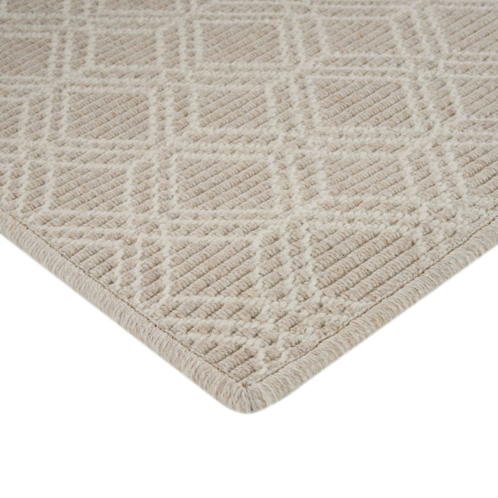 Close-up of cream-colored carpet with geometric textured pattern. Soft plush.