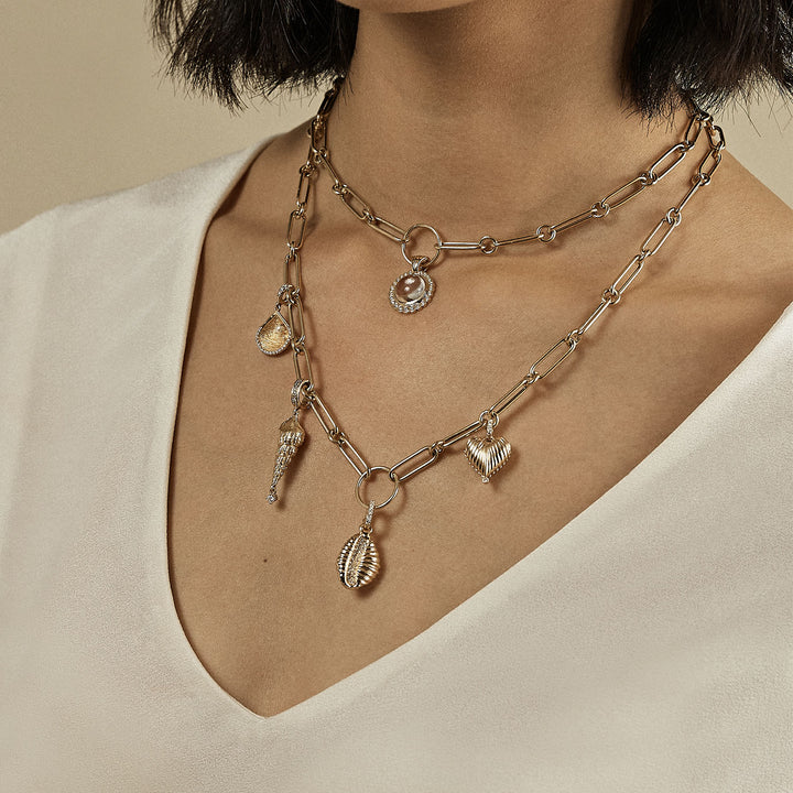 Layered metallic necklaces on person's chest, showcasing various charms.