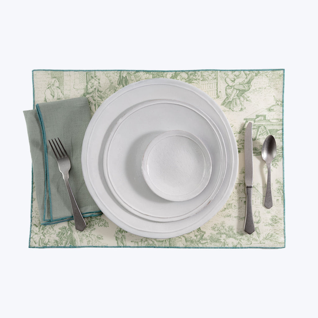 Neatly arranged table with white plates, cutlery, and botanical placemat.