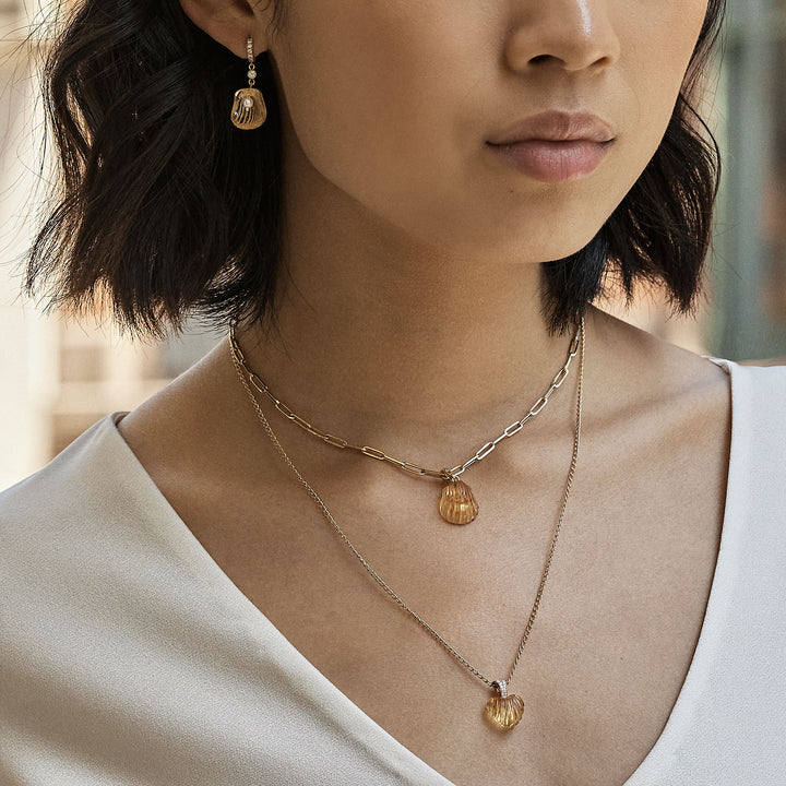 Elegant woman wears coordinating gold jewelry set with ribbed charms.