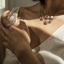 Luxurious jewelry adorns shoulders and fingers in elegant close-up.