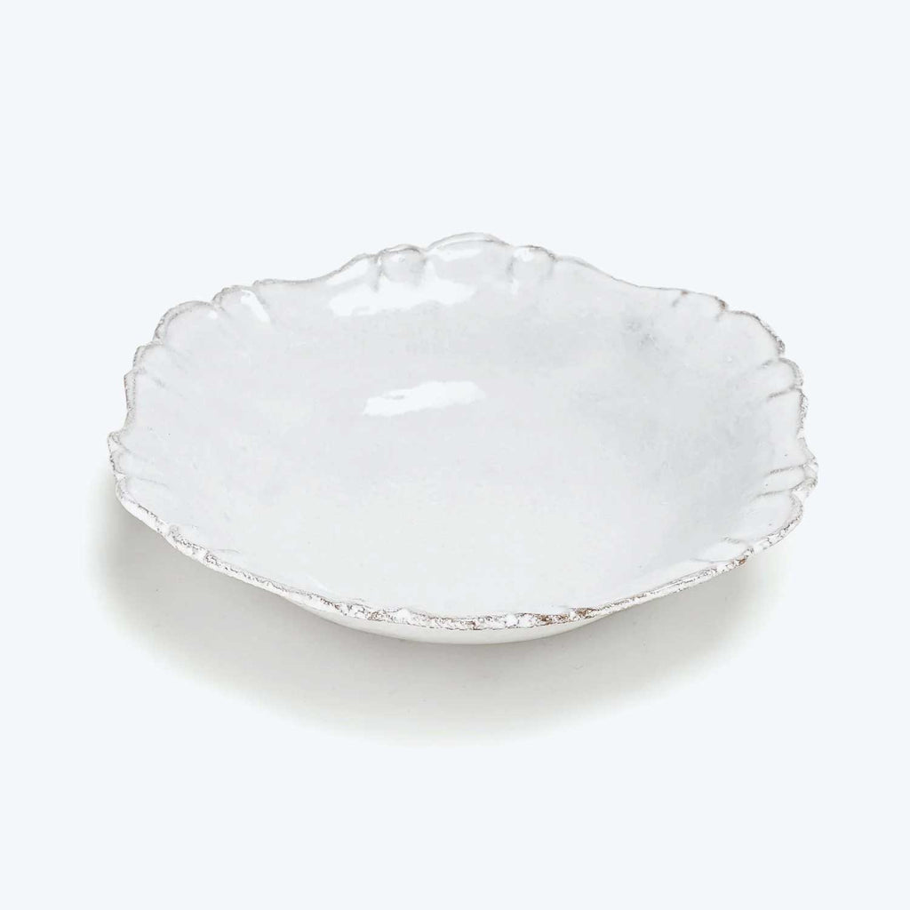 White scalloped-edge ceramic plate on plain background with rustic texture.