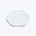Elegant white scalloped-edge plate on minimalist white background.