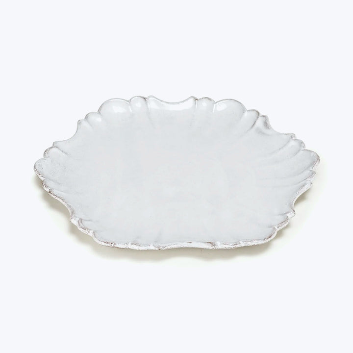 White ceramic plate with scalloped edge mimicking seashell design.