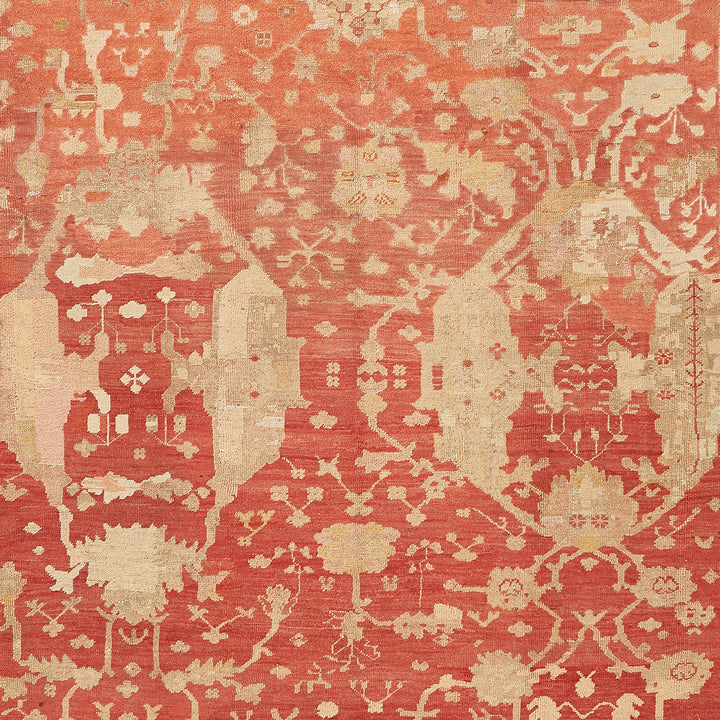 Antique rug with faded red pattern showcases intricate craftsmanship.