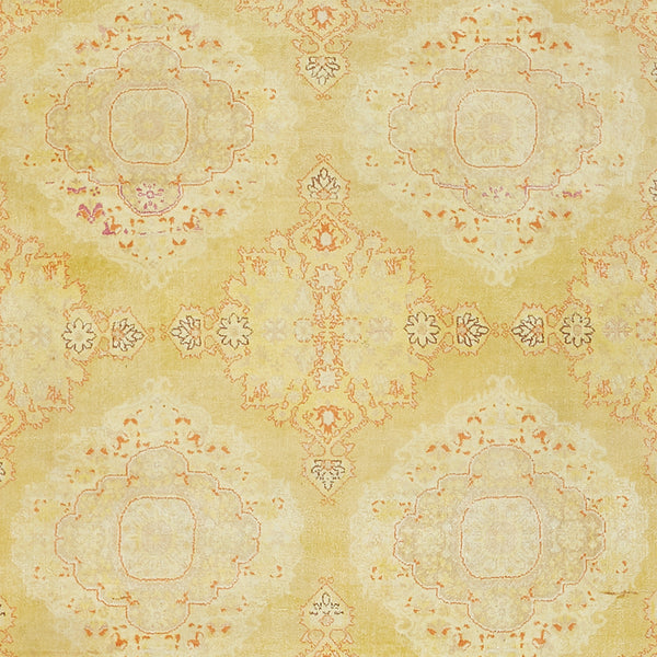 Vintage carpet with symmetrical, ornate pattern in soft, muted hues.